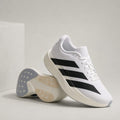 A pair of white Adidas running shoes with black three-stripes, shown on a light gray studio background with one shoe standing upright and the other lying on its side to display the sole.