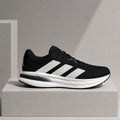 A black and white Adidas running shoe displayed on a minimalist gray pedestal against a neutral gray background.